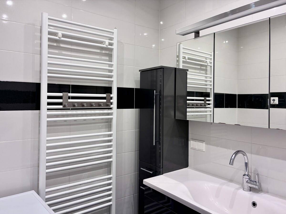 Funktionales Badezimmer mit beheiztem Handtuchhalter, Waschbecken und Spiegelschrank.