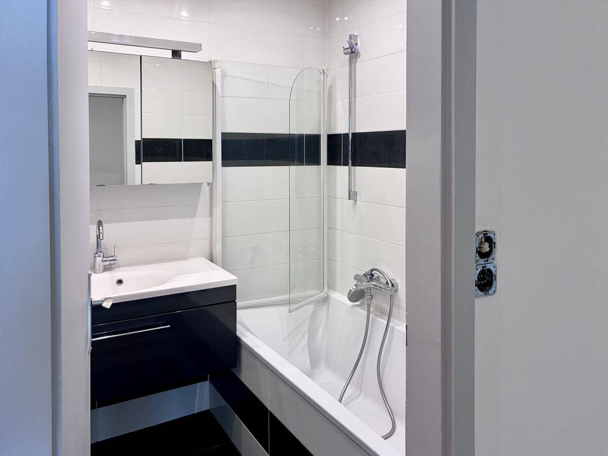 Modernes Badezimmer mit Badewanne, Duschabtrennung und stilvollen schwarz-weißen Fliesen.