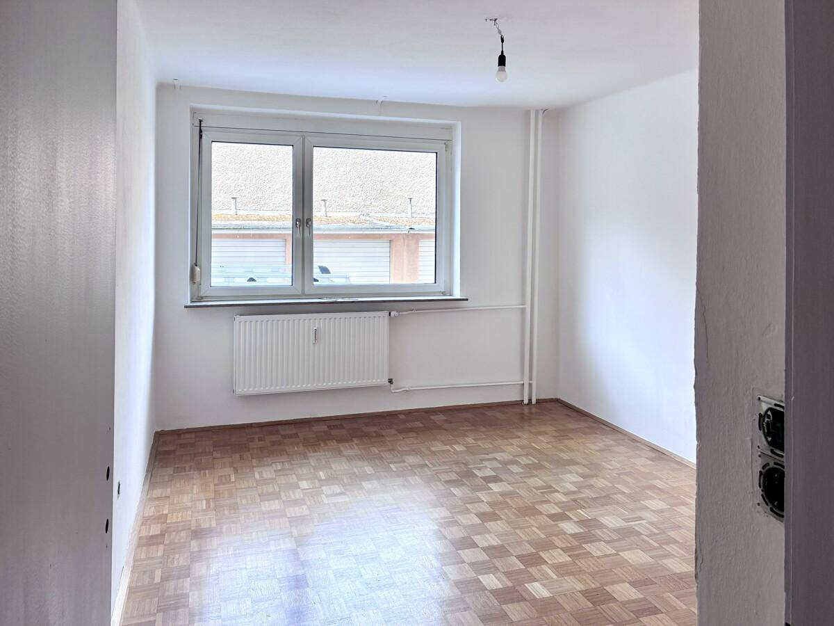 Ruhiges Schlafzimmer mit Parkettboden und Fenster, das einen Blick auf die Umgebung bietet.