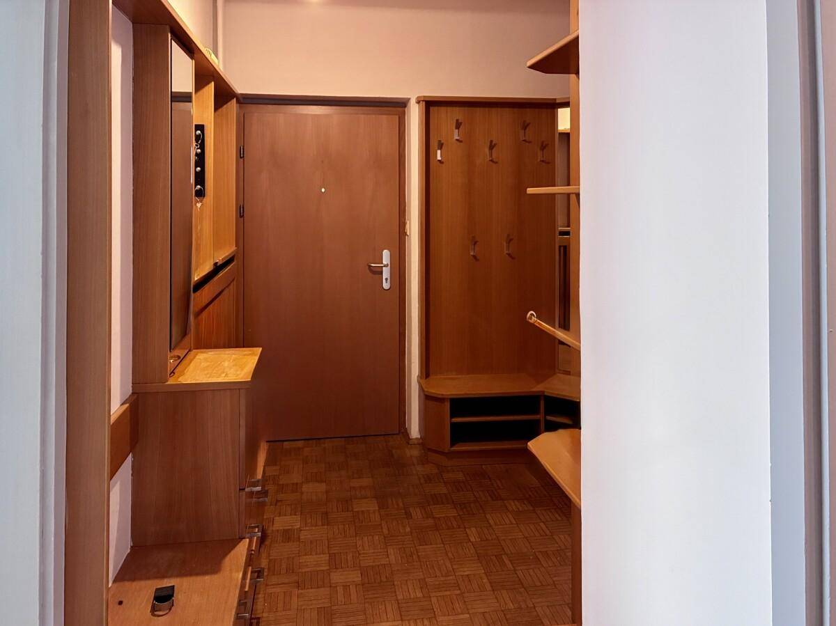 Eingangsbereich mit Holzgarderobe, Spiegel und einer Eingangstür.