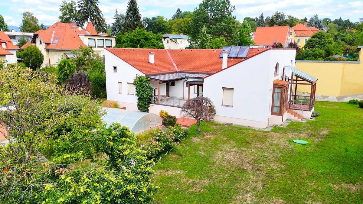 Weitläufiger Gartenbereich mit überdachtem Pool und Blick auf die umliegende Wohnbebauung.
