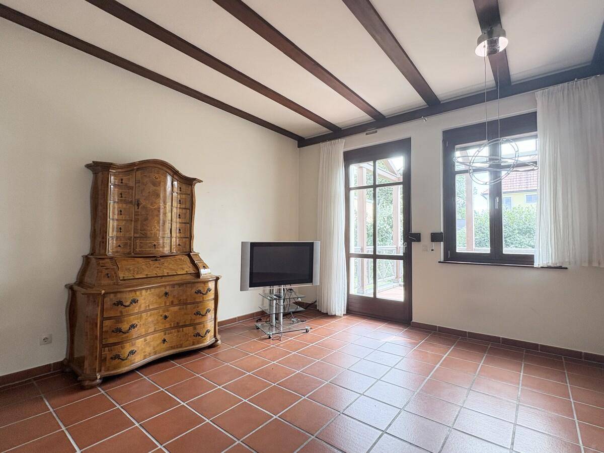 Gemütlicher Bereich mit Terrakottafliesen, Holzbalkendecke und einem antiken Schreibtischschrank.