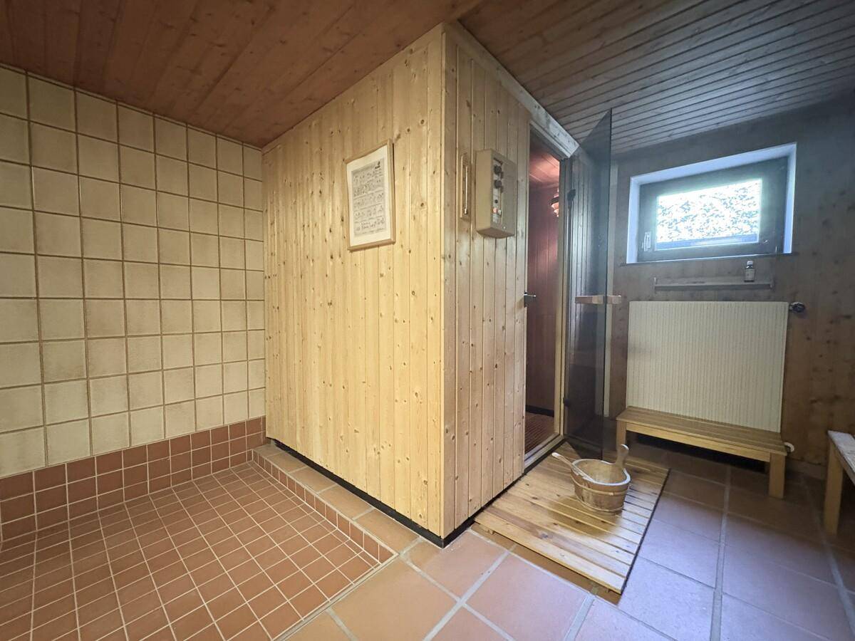 Gemütlicher Saunabereich mit Holztäfelung, Fliesenboden und einem kleinen Fenster.