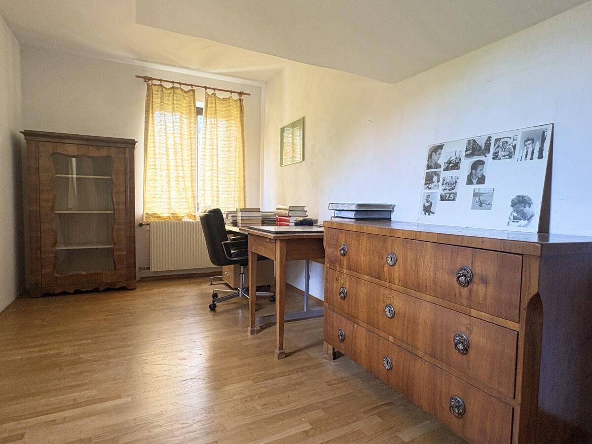 Helles Schlafzimmer mit Parkettboden, großem Fenster und klassischem Holzschrank.