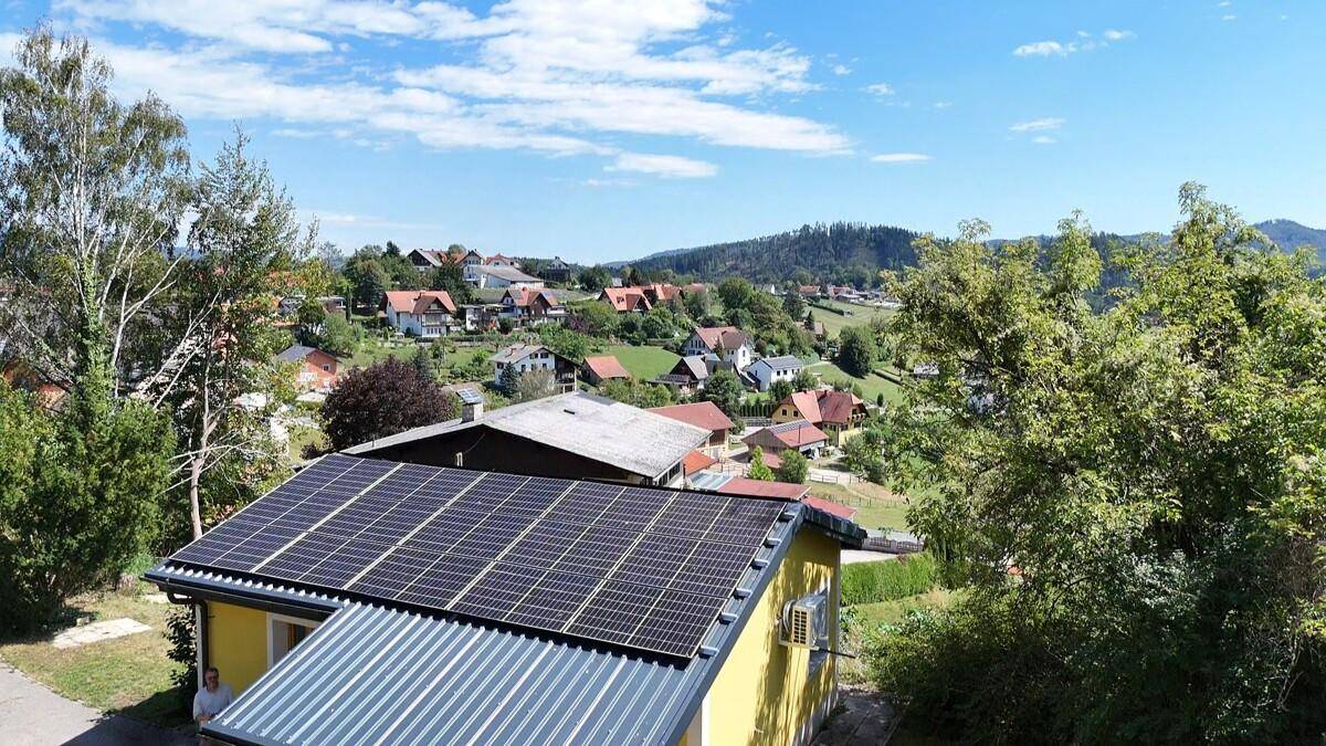 Luftaufnahme eines gelben Hauses mit Solaranlage und Klimaanlage an der Fassade.