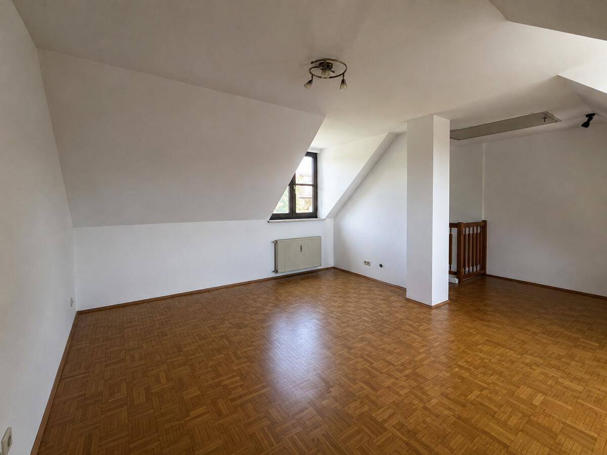 Großes Dachzimmer mit Parkettboden und schrägen Wänden, ideal für individuelle Gestaltung.