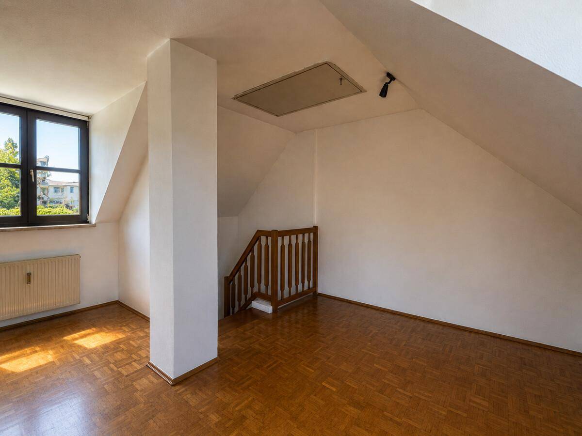 Geräumiges Dachzimmer mit Parkettboden und Fenster, ideal als Schlaf- oder Arbeitszimmer.