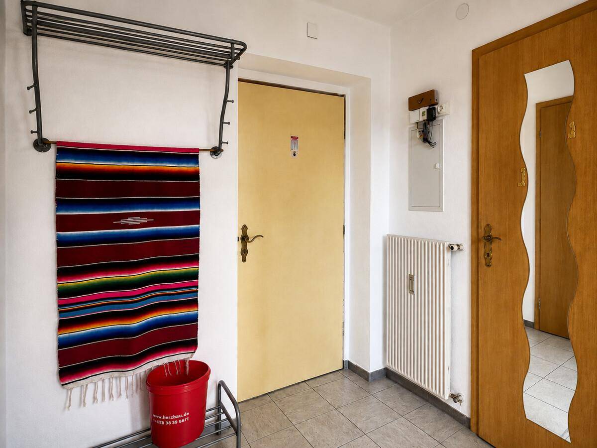 Eingangsbereich mit Fliesenboden, Garderobe und Holztüren, bietet praktischen Stauraum.