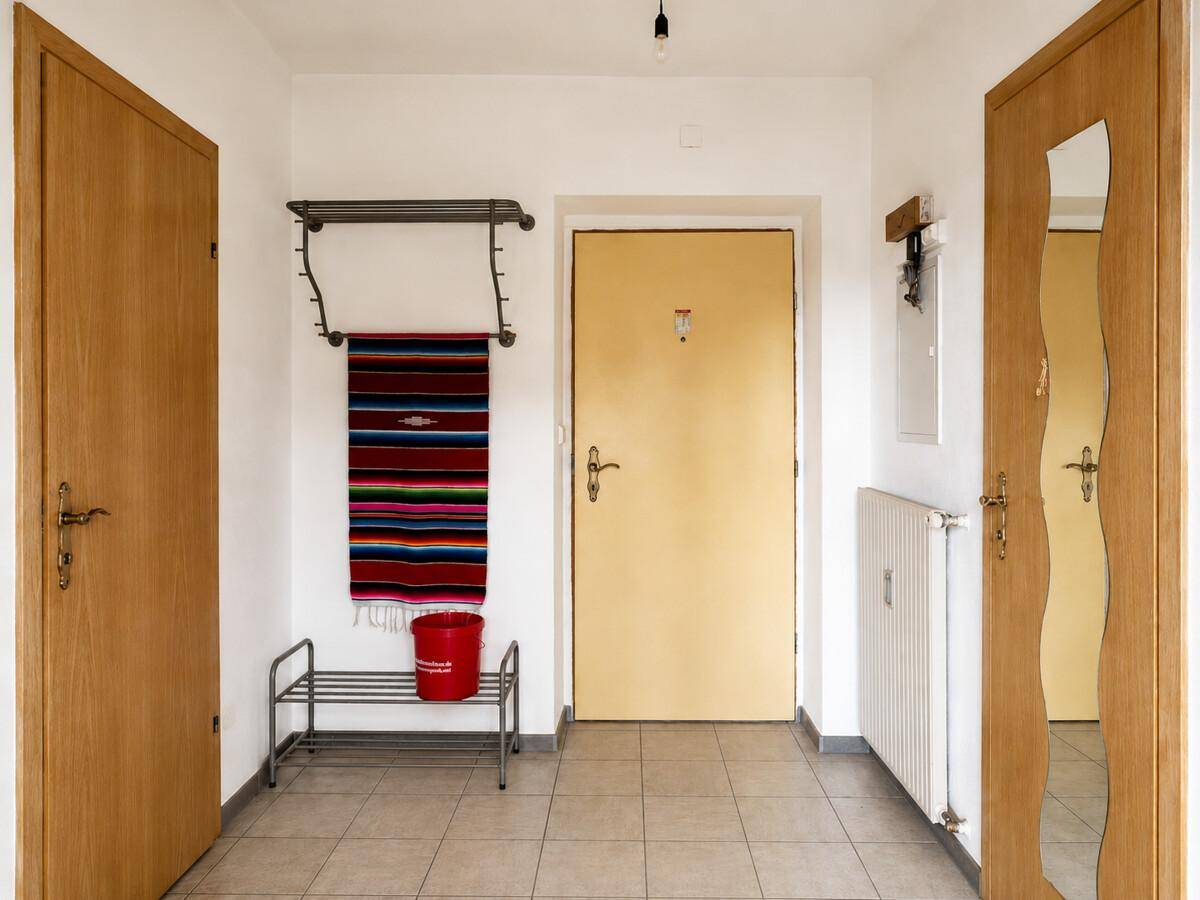 Heller Flur mit Fliesenboden, Garderobe und Holztüren, einladender Eingangsbereich.