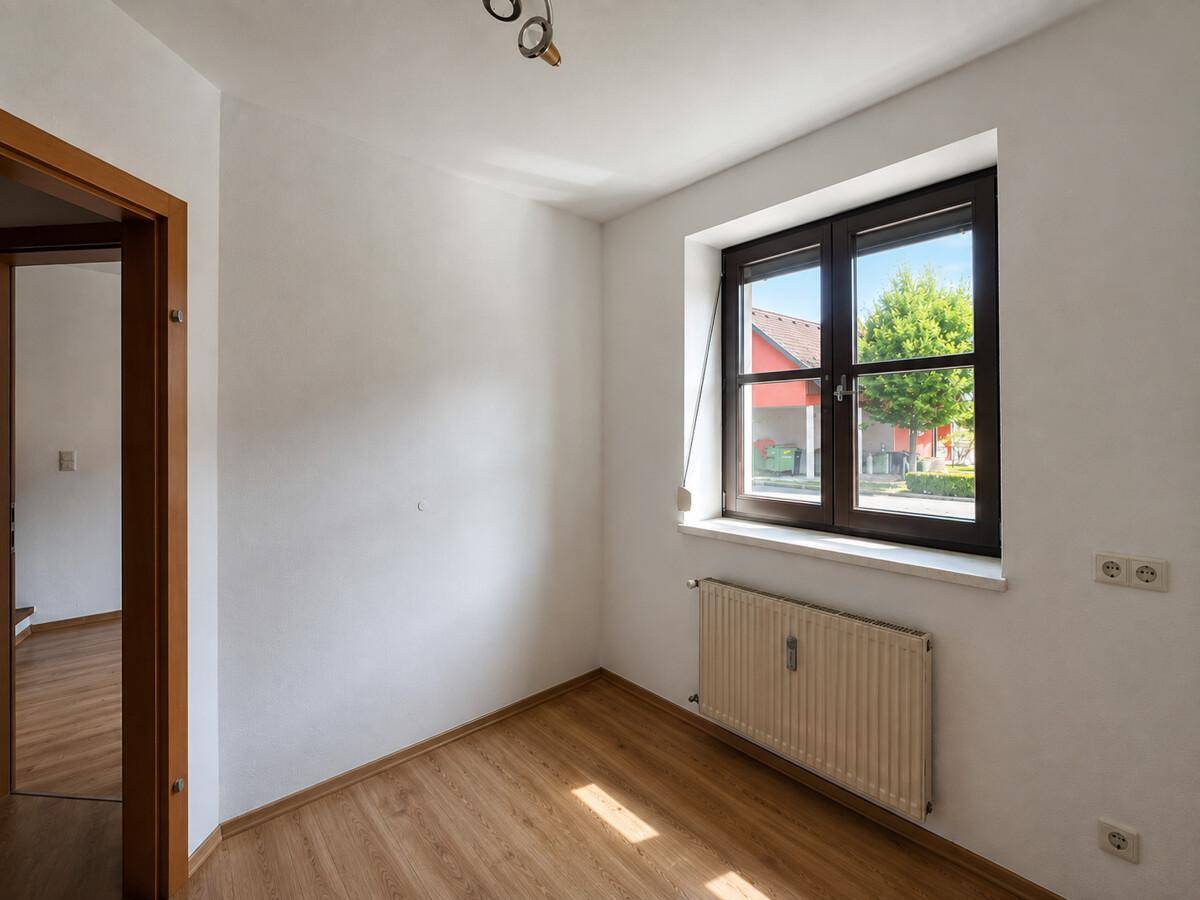 Helles Zimmer mit Laminatboden und großem Fenster, ideal als Schlaf- oder Arbeitszimmer.
