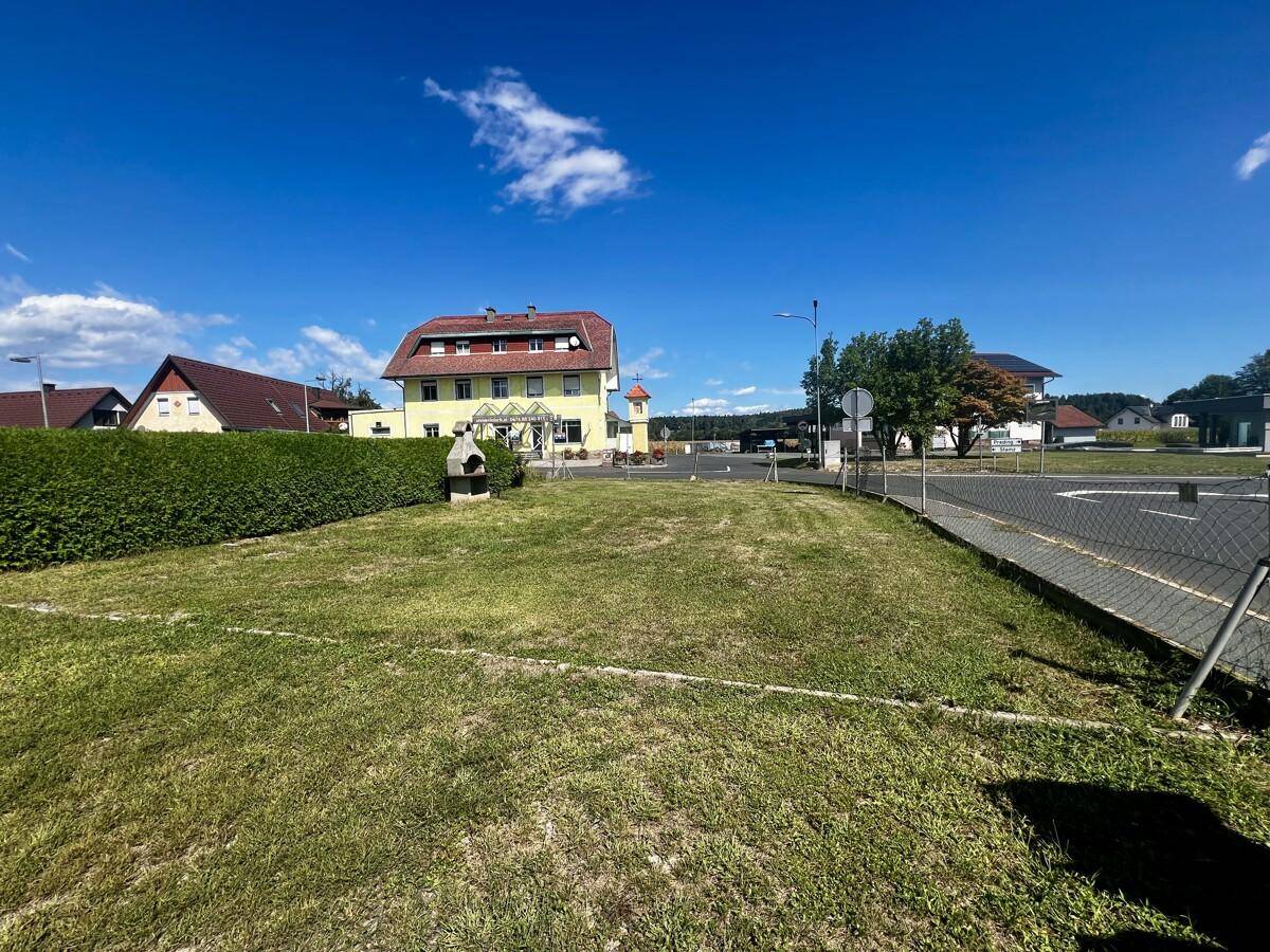 Gepflegte Rasenfläche mit Grillplatz und Hecke, ideal für entspannte Stunden im Freien.