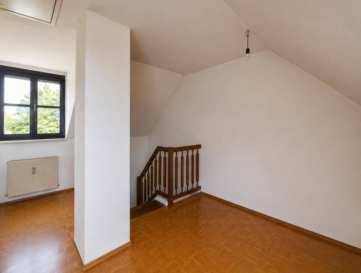 Helles Dachzimmer mit Parkettboden und Fenster, ideal als Schlaf- oder Arbeitsbereich.