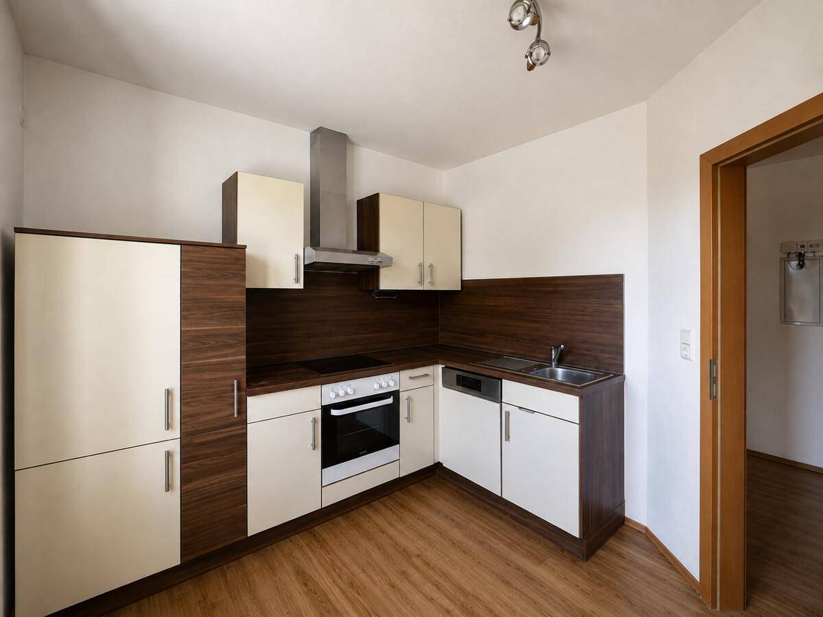 Moderne Einbauküche mit hellen und dunklen Holzfronten, Kochfeld und Spüle.