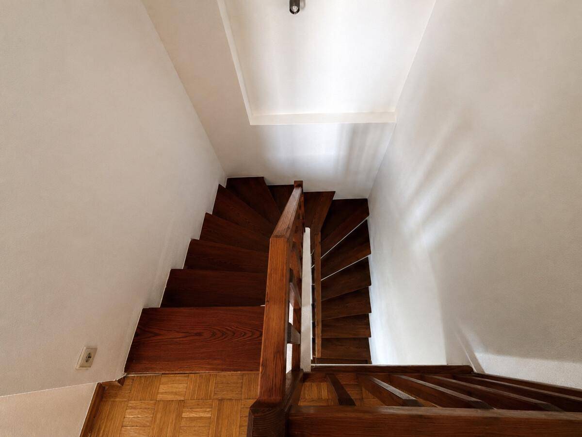 Holztreppe mit Geländer führt in die obere Etage, gut erhalten und funktional.