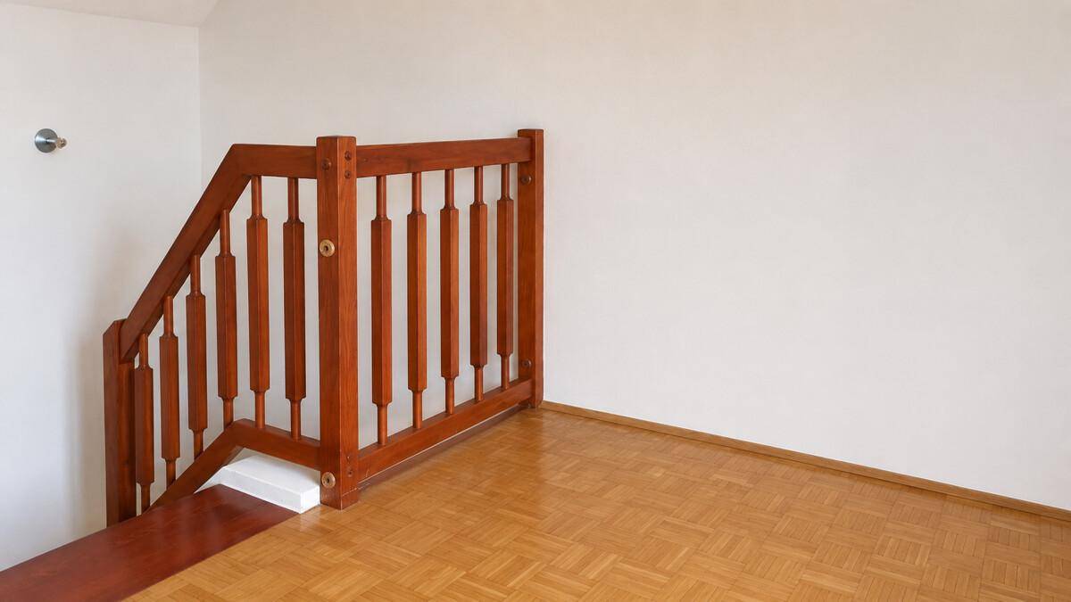 Detailansicht des Holzgeländers einer Treppe in einem hellen Dachgeschossbereich.