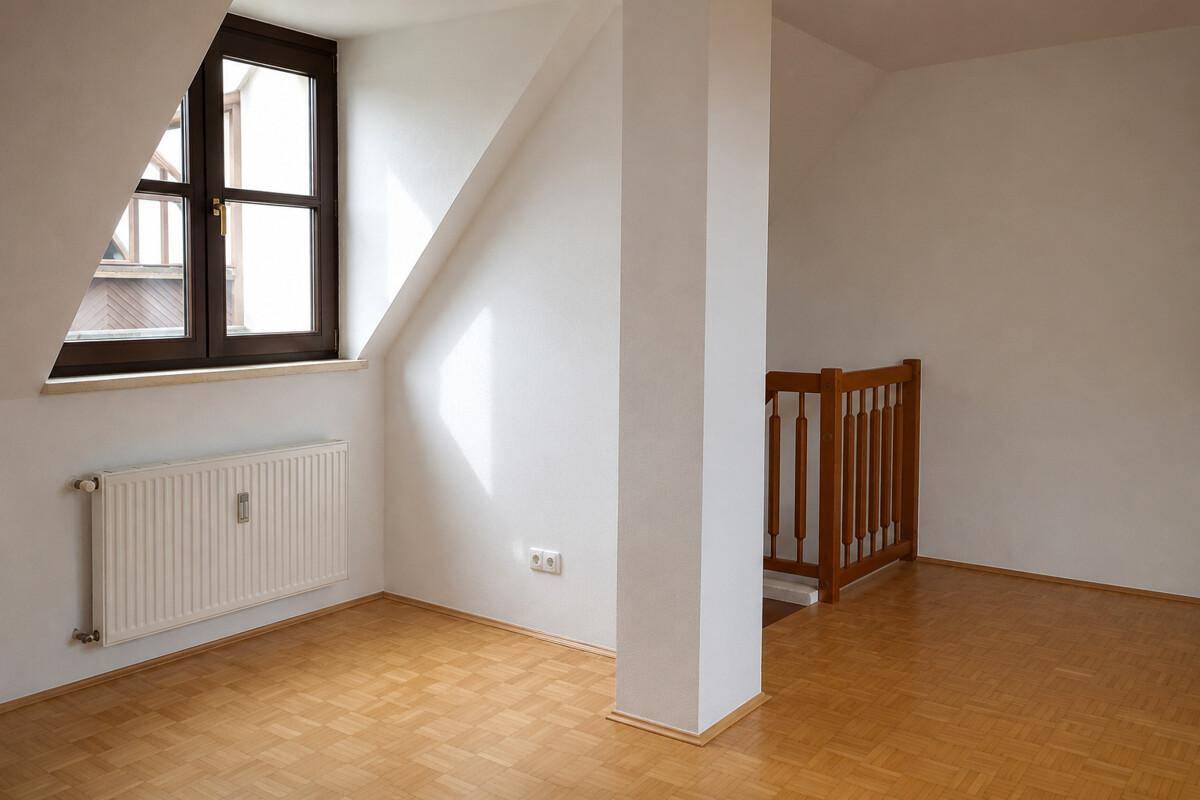 Freundlicher Dachbodenraum mit Parkettboden, schräger Decke und Holzgeländer zur Treppe.
