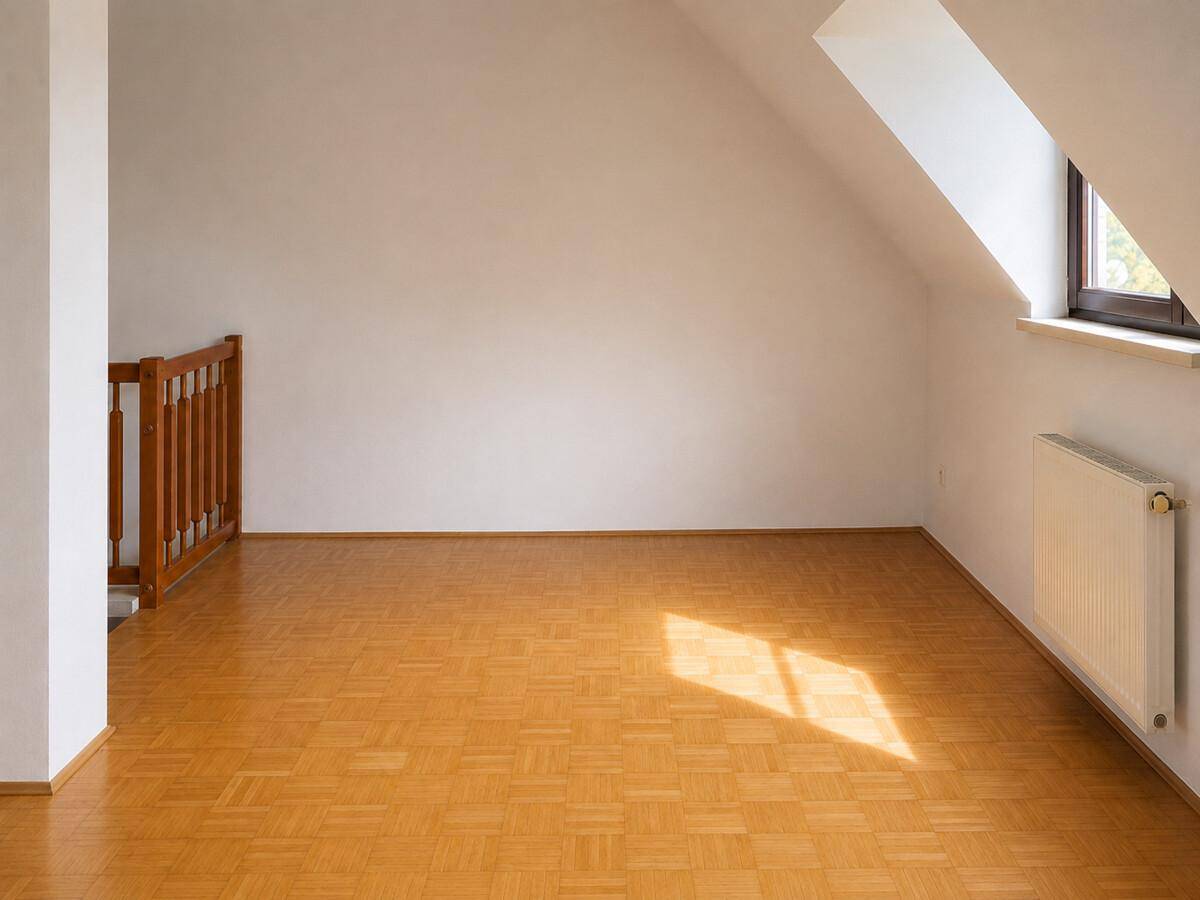 Heller Dachbodenraum mit schrägen Wänden, Parkettboden und Holzgeländer zur Treppe.