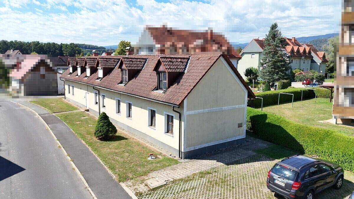 Luftaufnahme eines langgestreckten Gebäudes mit mehreren Gaubenfenstern und einem gepflegten Außenbereich.