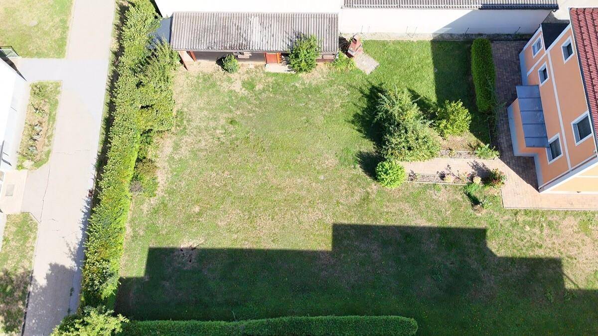 Großer, grüner Gartenbereich neben dem Haus mit Rasenfläche und Heckenbegrenzung.