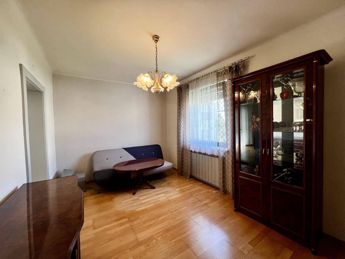 Esszimmer oder zusätzlicher Wohnbereich mit Sofa, Vitrine und Parkettboden, hell beleuchtet.