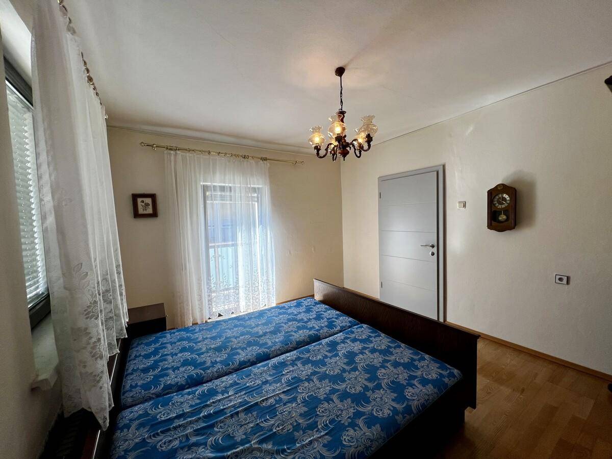 Schlafzimmer mit zwei Einzelbetten, Fenster und Parkettboden, hell und freundlich gestaltet.