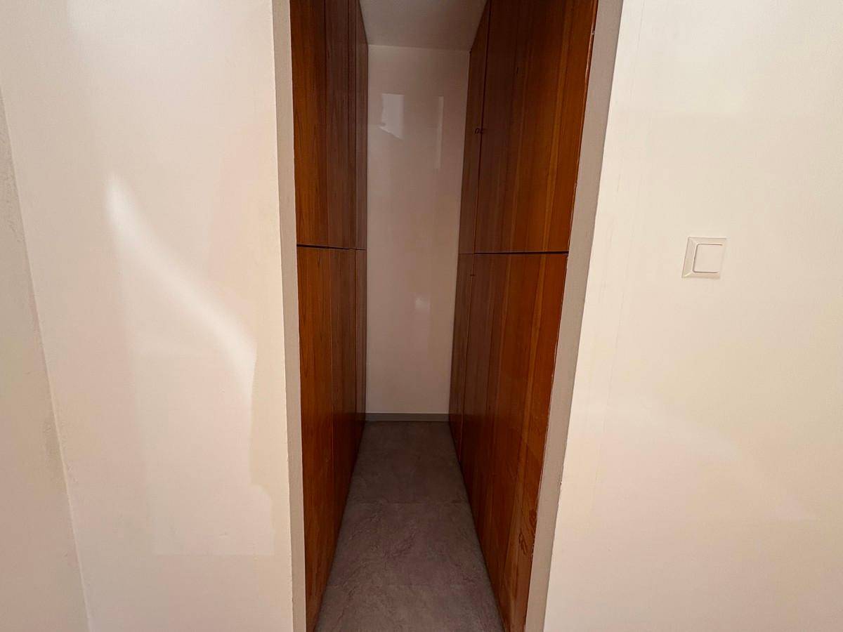 Praktischer begehbarer Kleiderschrank mit eingebauten Holzschränken auf beiden Seiten.