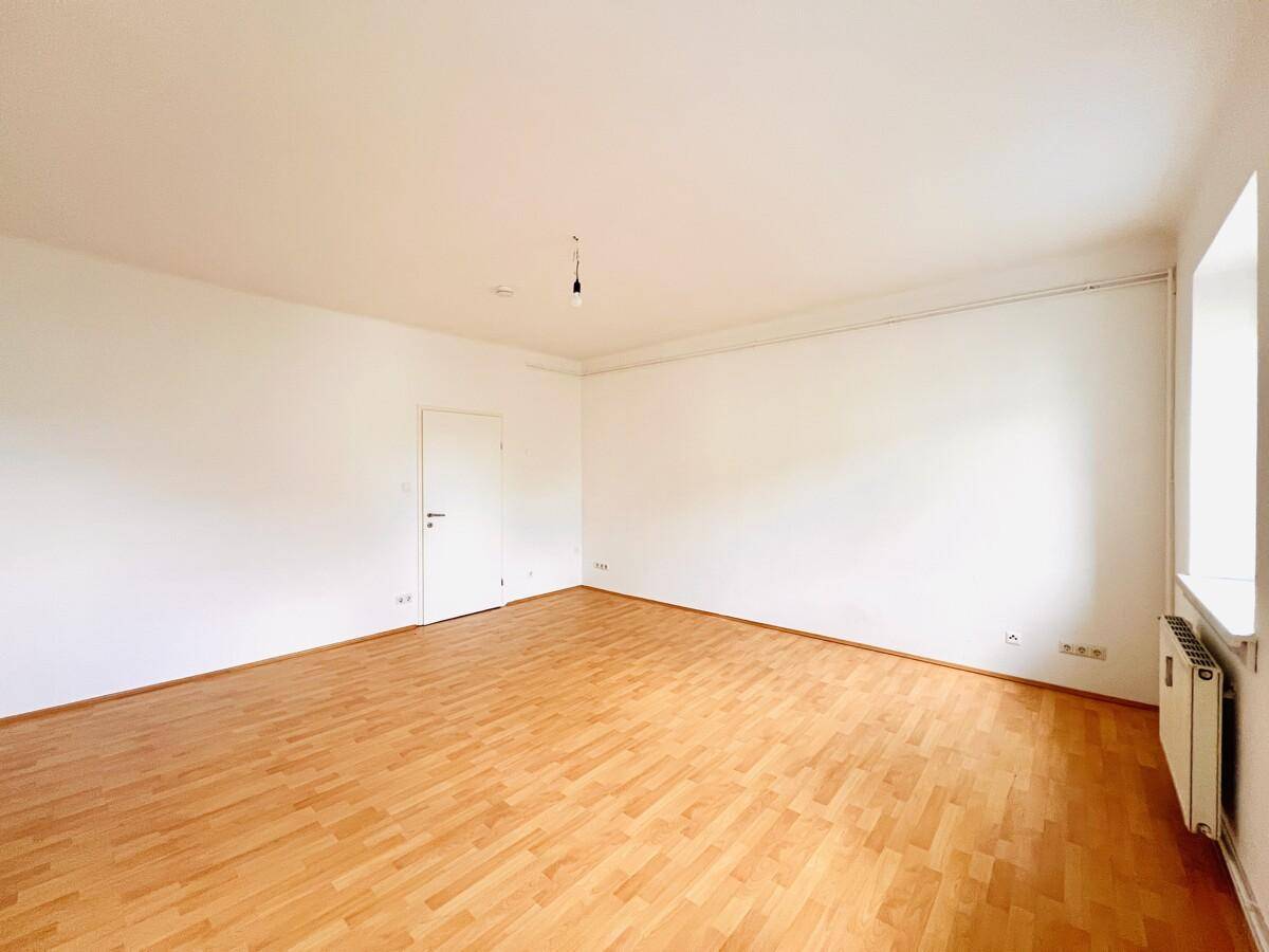 Helles Wohnzimmer mit Holzboden und weiß gestrichenen Wänden, bereit zur Einrichtung.