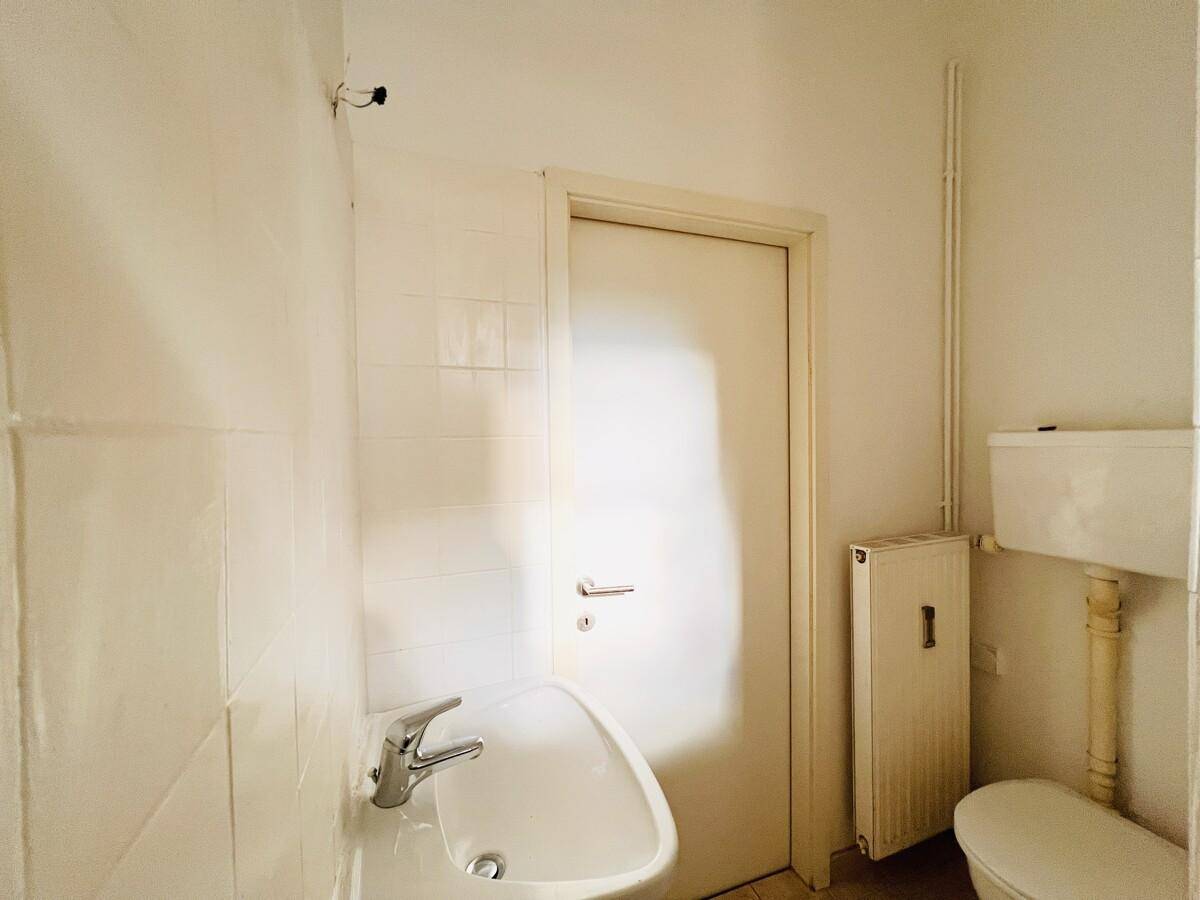 Kleines Gäste-WC mit Waschbecken und Toilette, hell gefliest.