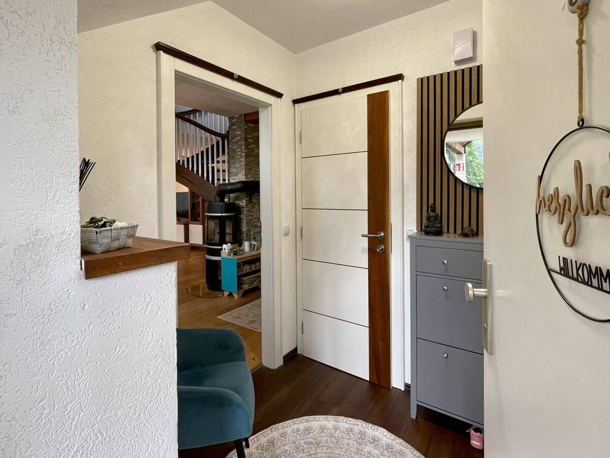 Freundlicher Flur mit modernem Schuhschrank und Blick in den offenen Wohnbereich mit Kamin.