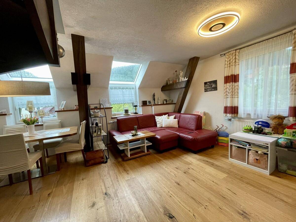 Offener Wohn-Essbereich mit rotem Sofa, Esstisch und mehreren Dachfenstern für viel Licht.