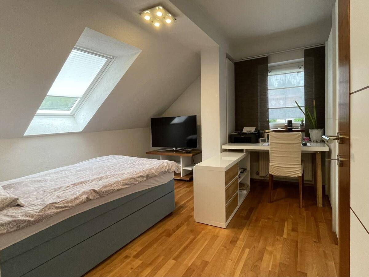 Multifunktionaler Raum mit Bett, Schreibtisch und Dachfenster, ideal als Schlaf- oder Arbeitszimmer.