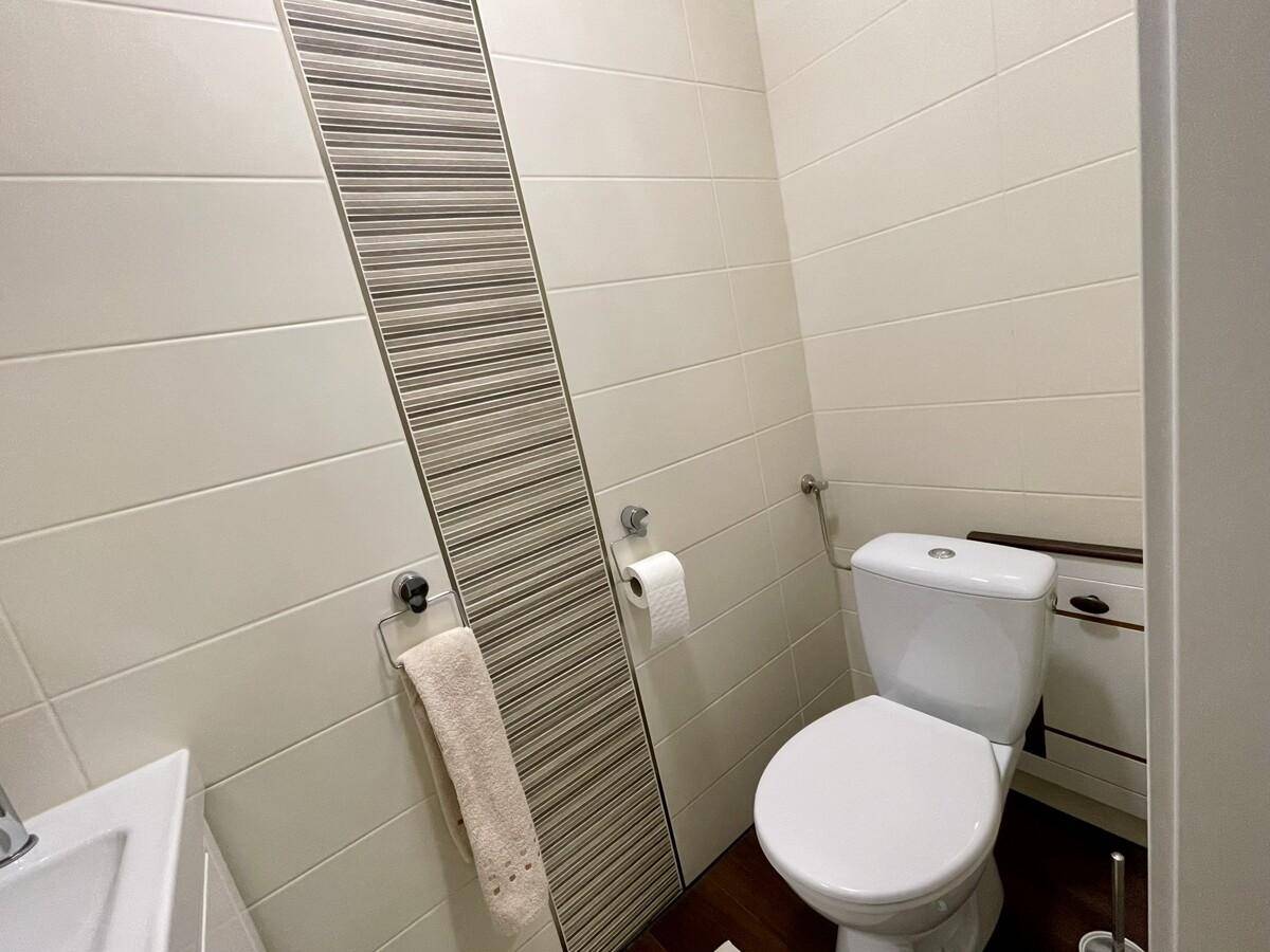 Modern gefliestes Gäste-WC mit Toilette und stilvoller Wandgestaltung.