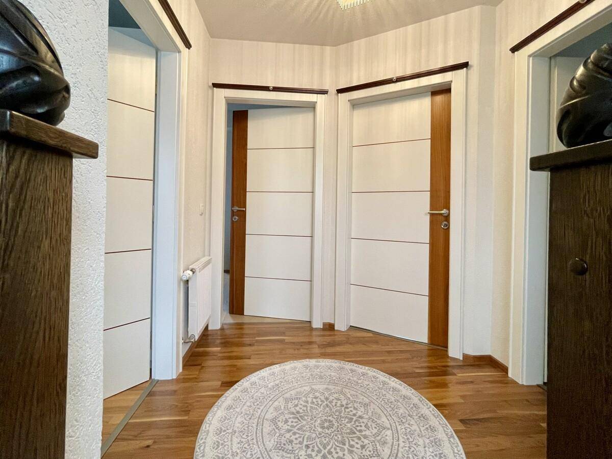 Heller Flur mit mehreren modernen Türen und durchgehendem Holzboden.