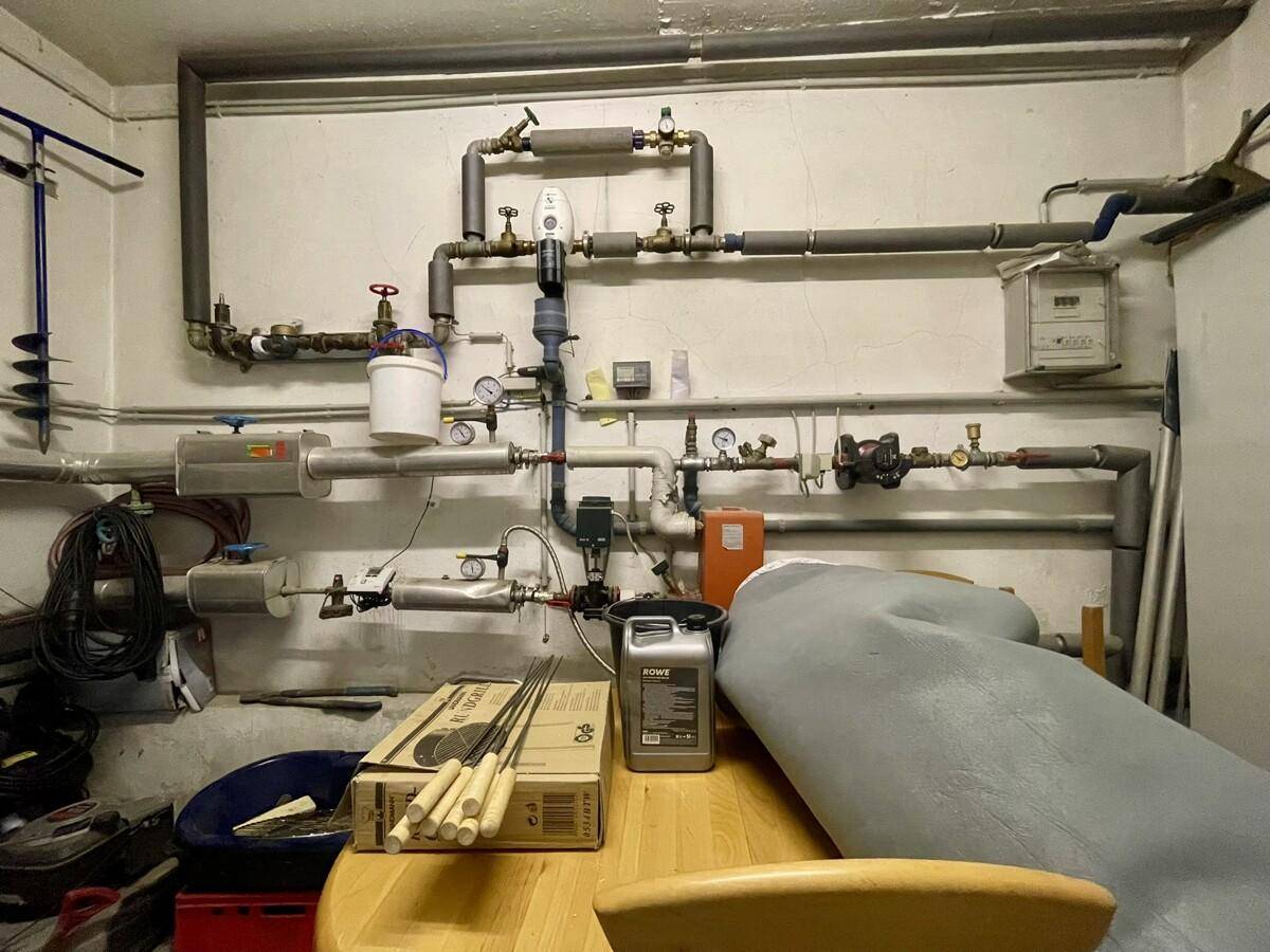 Technikraum mit komplexen Rohrleitungen und Ventilen an der Wand, für die Hausversorgung.