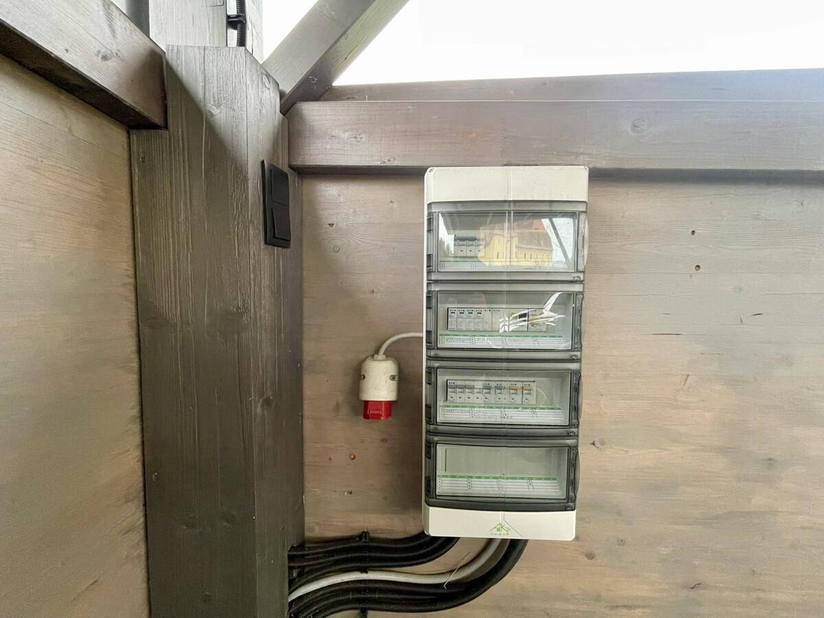 Elektrischer Sicherungskasten und Verkabelung an einer Holzwand, Teil der Gebäudeinfrastruktur.