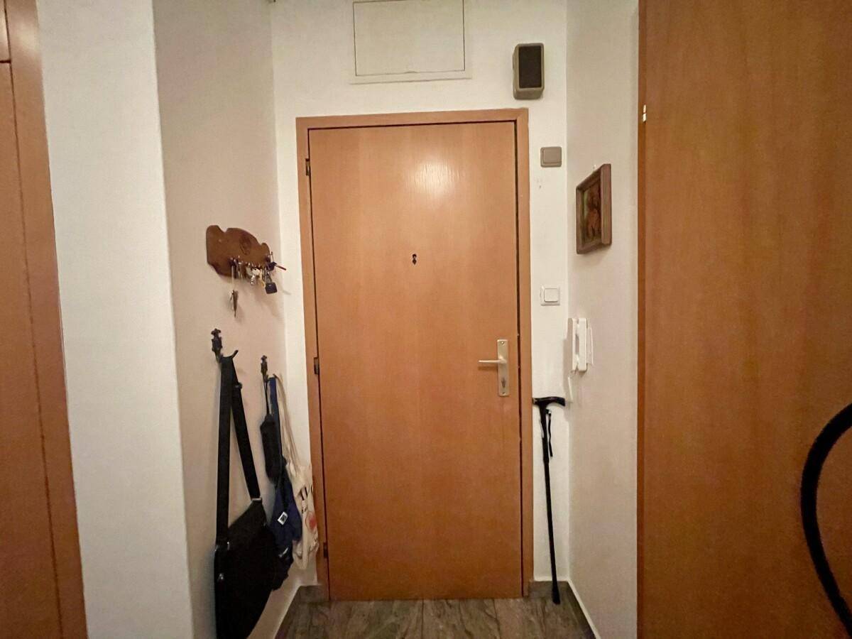 Eingangsbereich mit Holztür, Garderobe und Fliesenboden, einladend gestaltet.