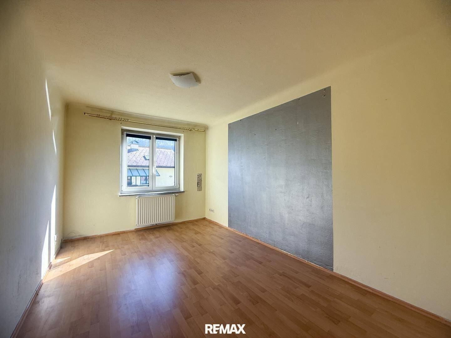 Leeres Zimmer mit Holzboden und einem Fenster, bereit für individuelle Gestaltung.