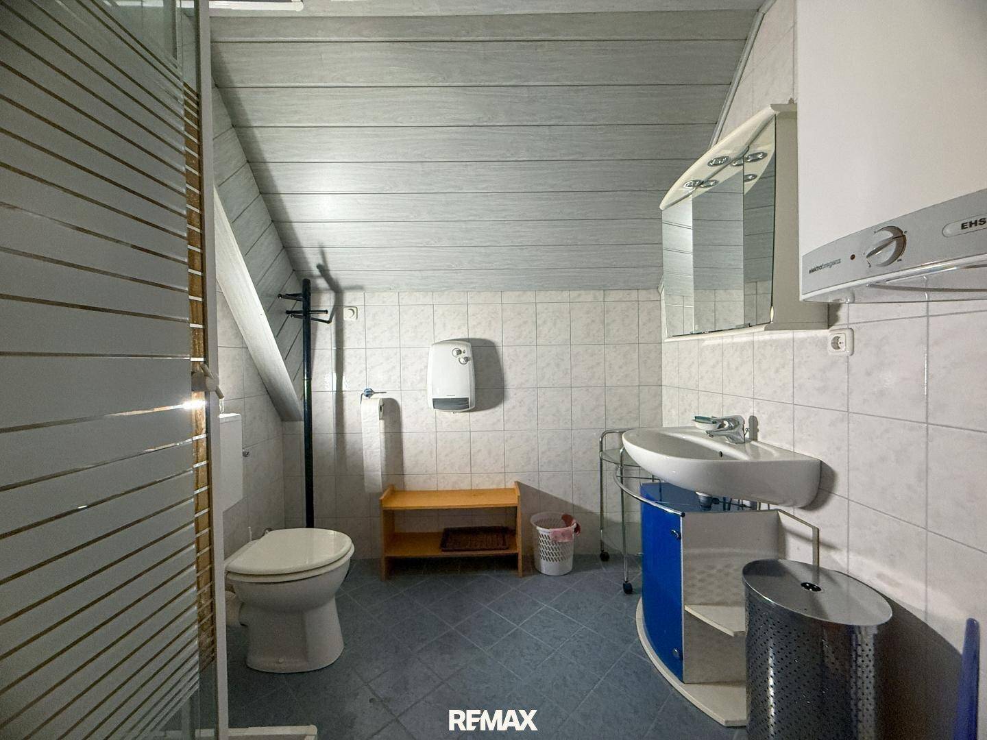Badezimmer im Dachgeschoss mit Dusche, WC und Waschbecken unter schräger Decke.