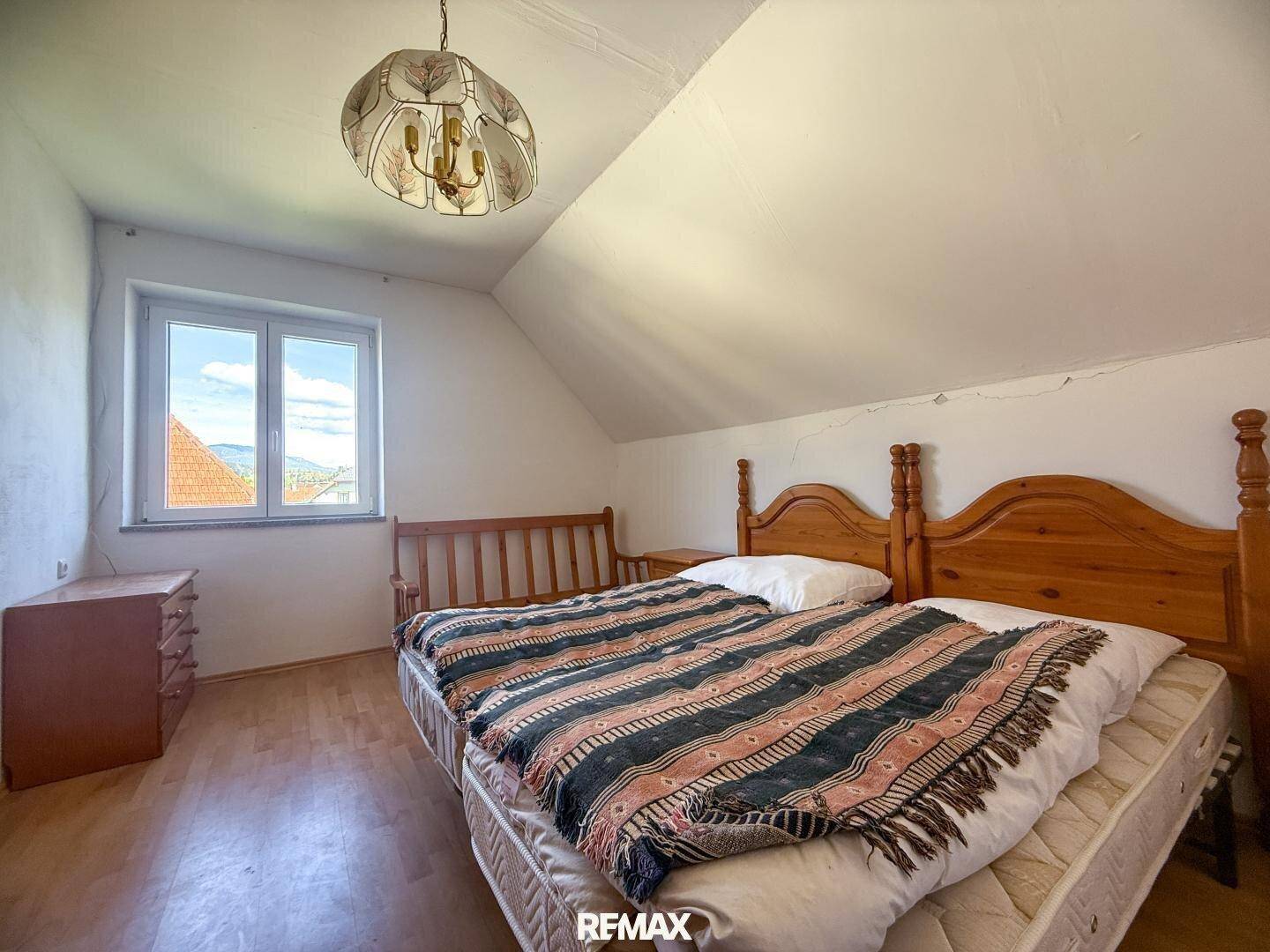 Gemütliches Schlafzimmer im Dachgeschoss mit Holzboden, zwei Betten und schrägen Wänden.