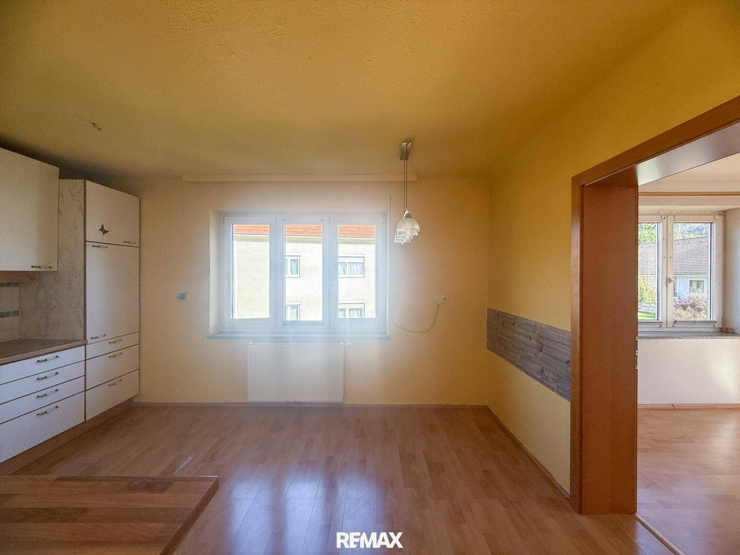Helle Küche mit Einbauschränken, Holzboden und Fenster, bereit für neue Geräte.