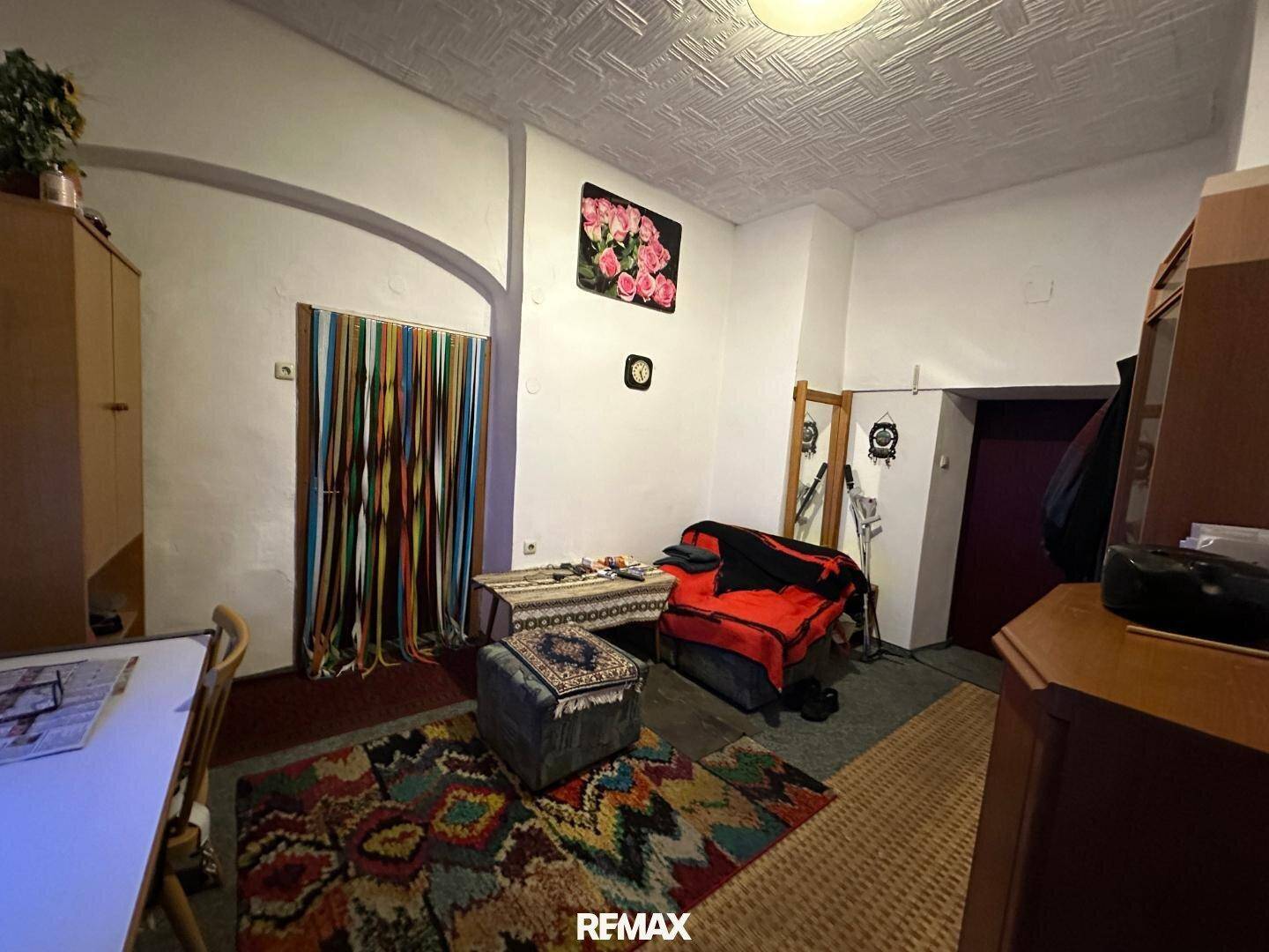 Gemütliches Wohnzimmer mit Teppichen, einem Sofa und traditioneller Deckenverkleidung.