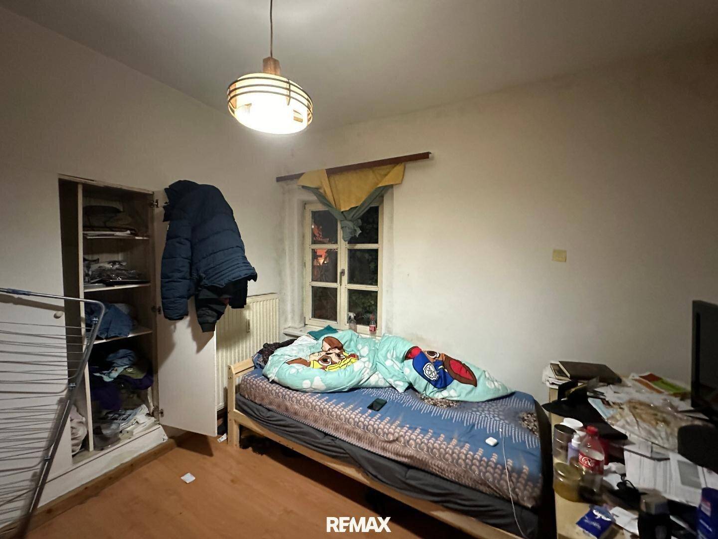 Kleines Schlafzimmer mit Holzboden, einem Einzelbett und einem Fenster mit Blick nach draußen.