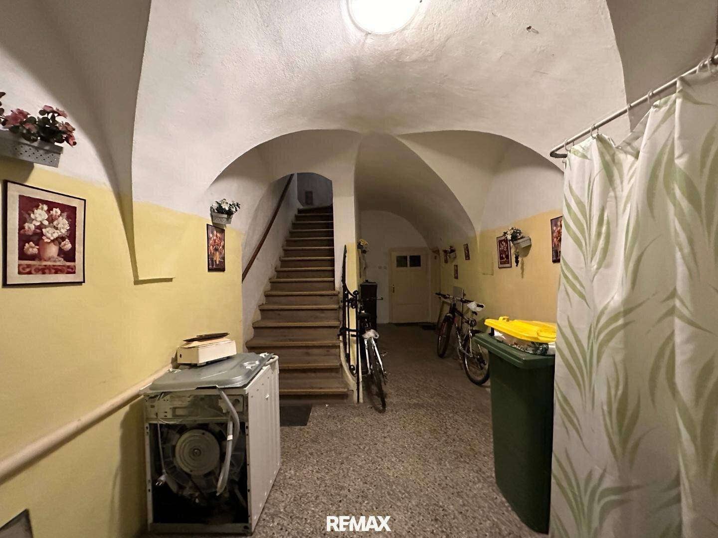 Gewölbter Eingangsbereich mit Treppe, Fliesenboden und Abstellmöglichkeiten für Fahrräder.