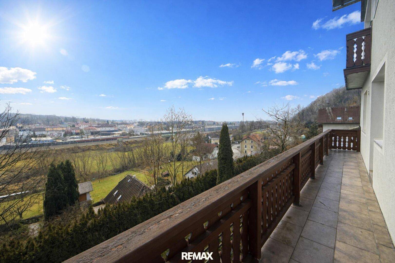 Langer Balkon mit Holzbalkongeländer und weitem Blick über die Landschaft und Stadt.