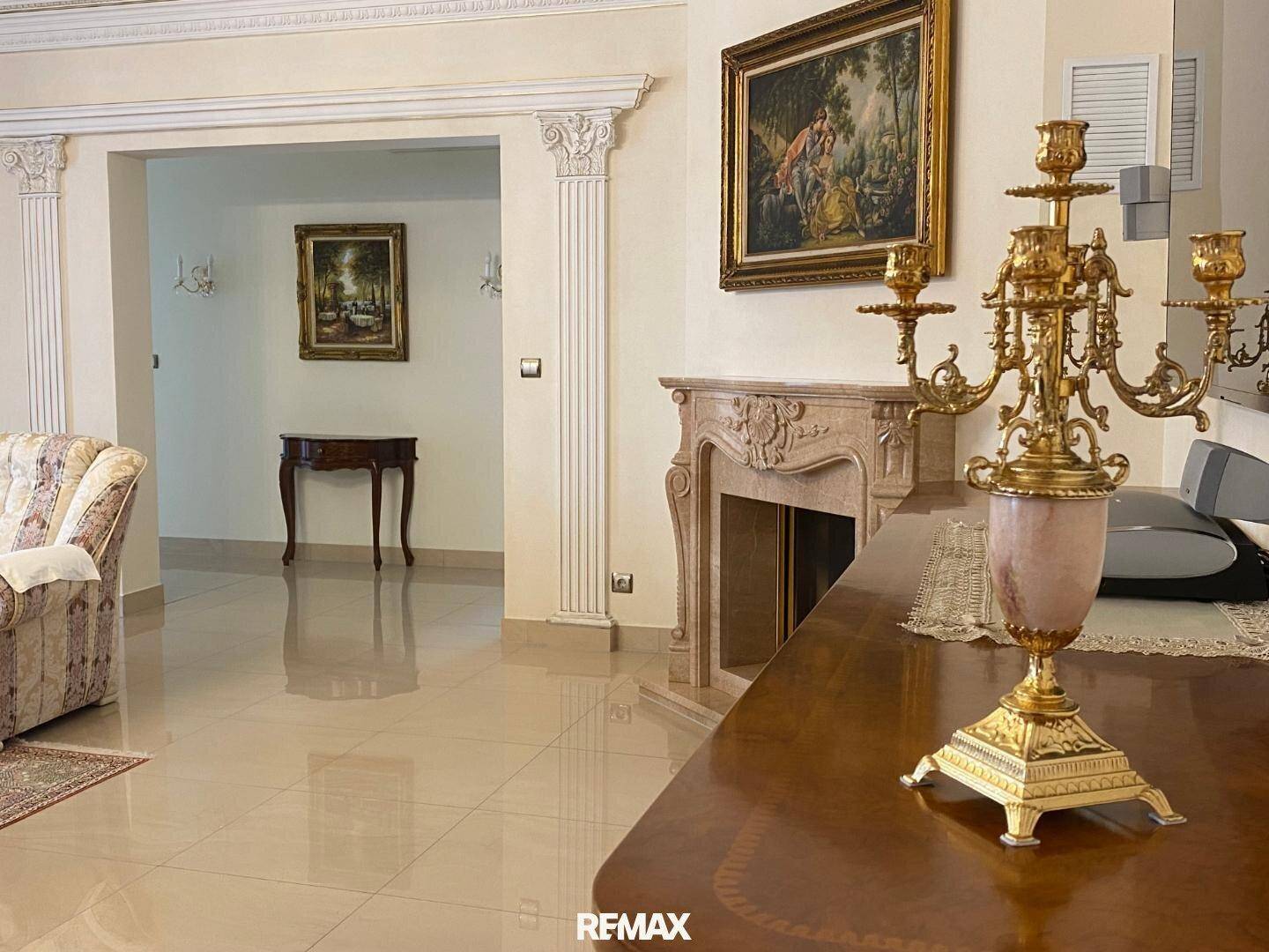 Elegantes Wohn-Esszimmer mit klassischem Kamin, glänzenden Fliesen und opulenten Dekorationen.