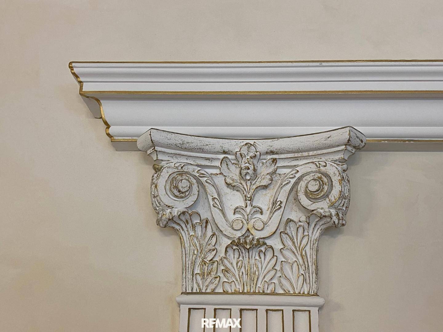 Detailaufnahme eines kunstvoll verzierten Säulenkapitells mit goldenen Akzenten.