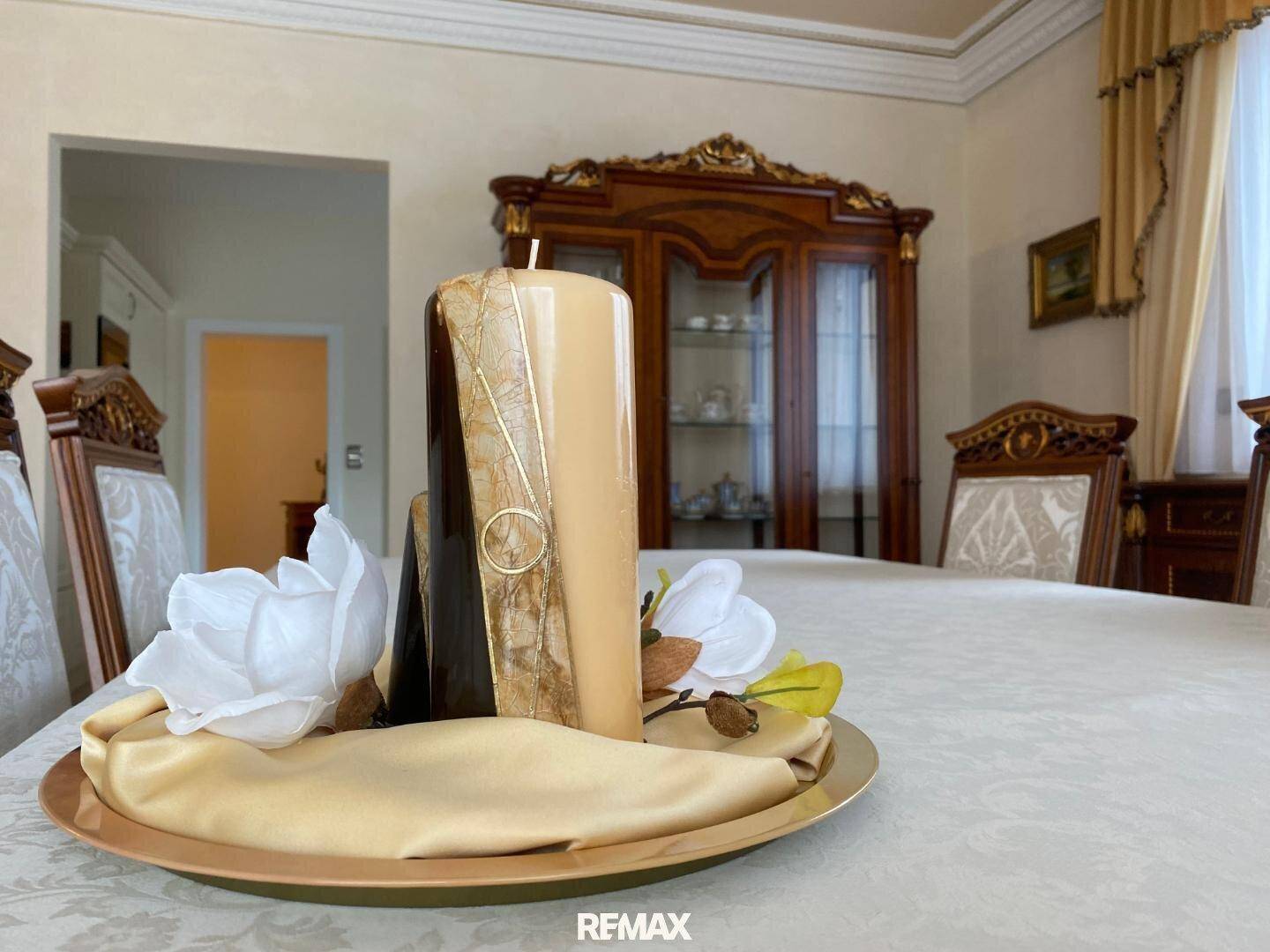 Dekorative Kerzenarrangement auf dem Esstisch, umgeben von eleganten Blumen und einem goldenen Tablett.