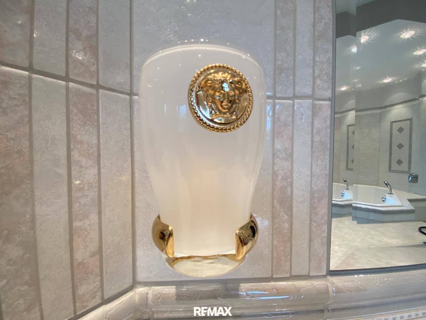 Detailaufnahme eines dekorativen Wandaccessoires mit goldenem Medaillon im luxuriösen Badezimmer.