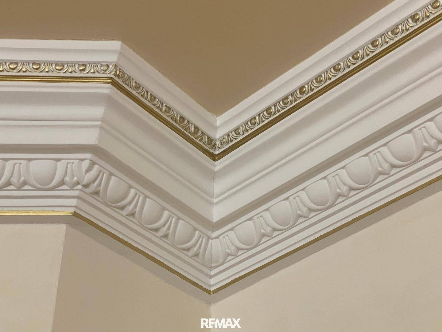 Detailansicht einer kunstvollen Deckenleiste mit goldenen Akzenten, die Eleganz verleiht.