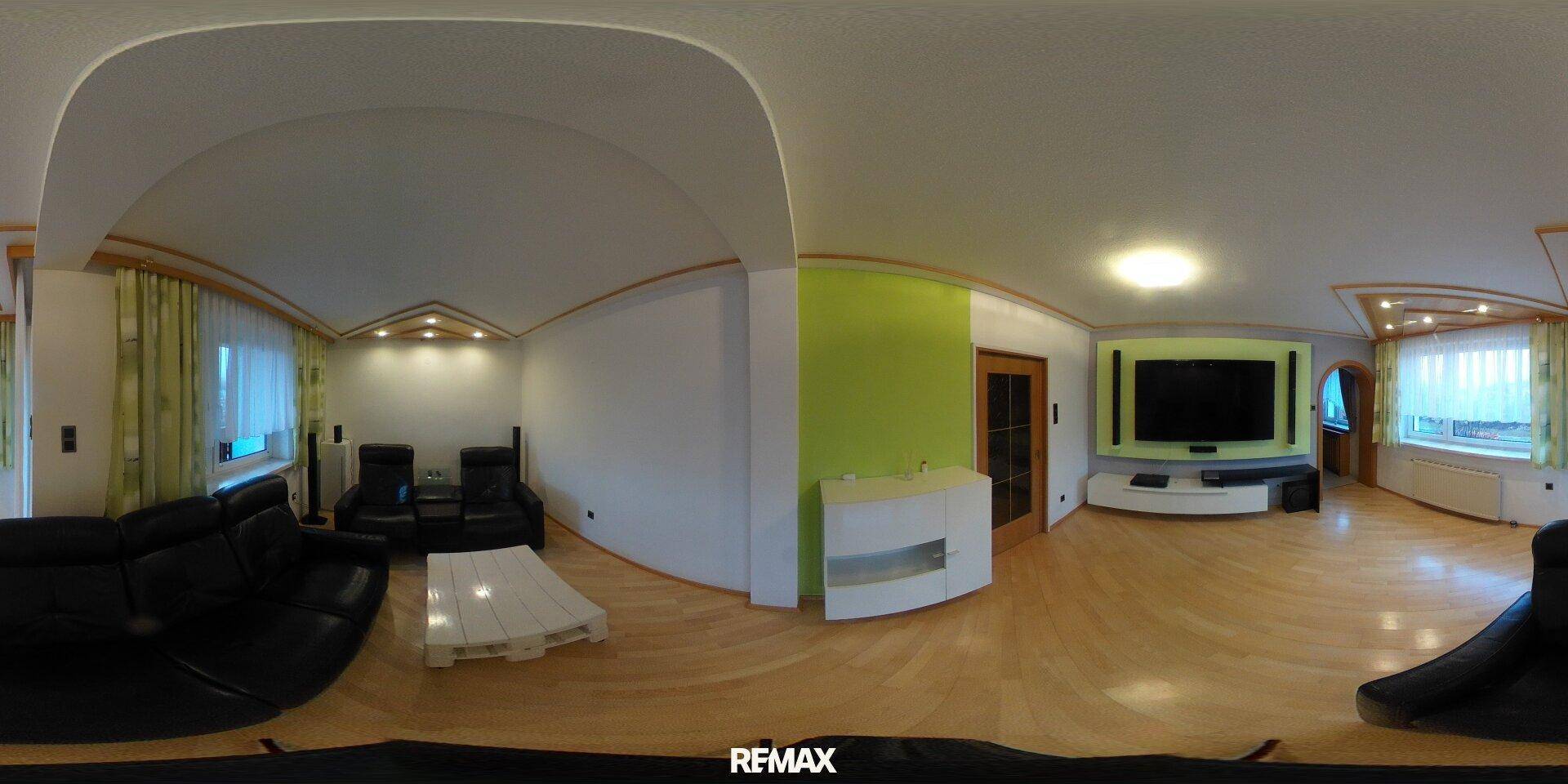 Helles Wohnzimmer mit Parkettboden, moderner Einrichtung und großem Fernseher.